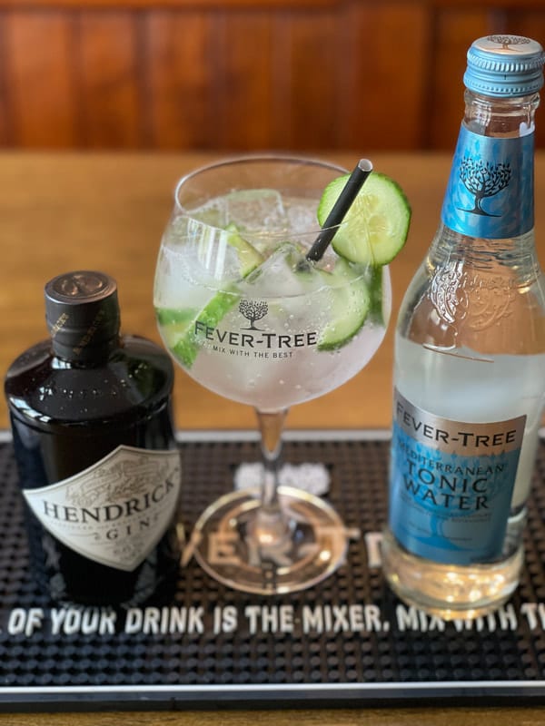A gin and tonic, poured over ice with cucumber